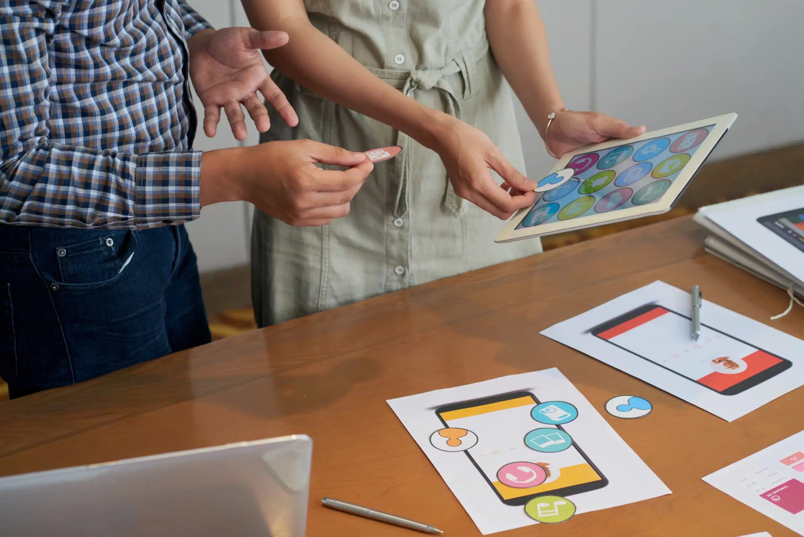 unrecognizable colleagues looking tablet trying different icons scaled
